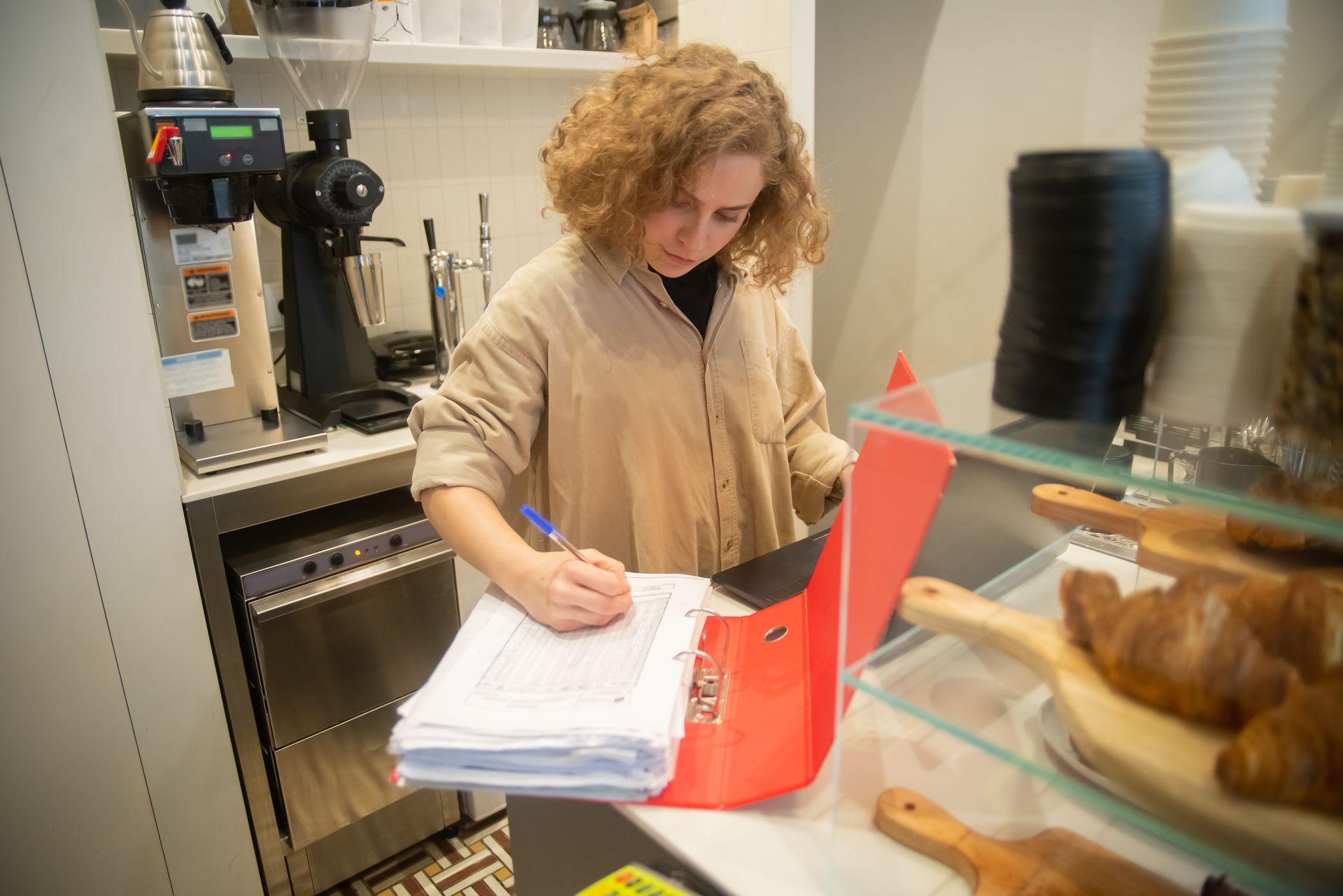 Commerçante classant ses factures fournisseurs papier dans une boulangerie-pâtisserie