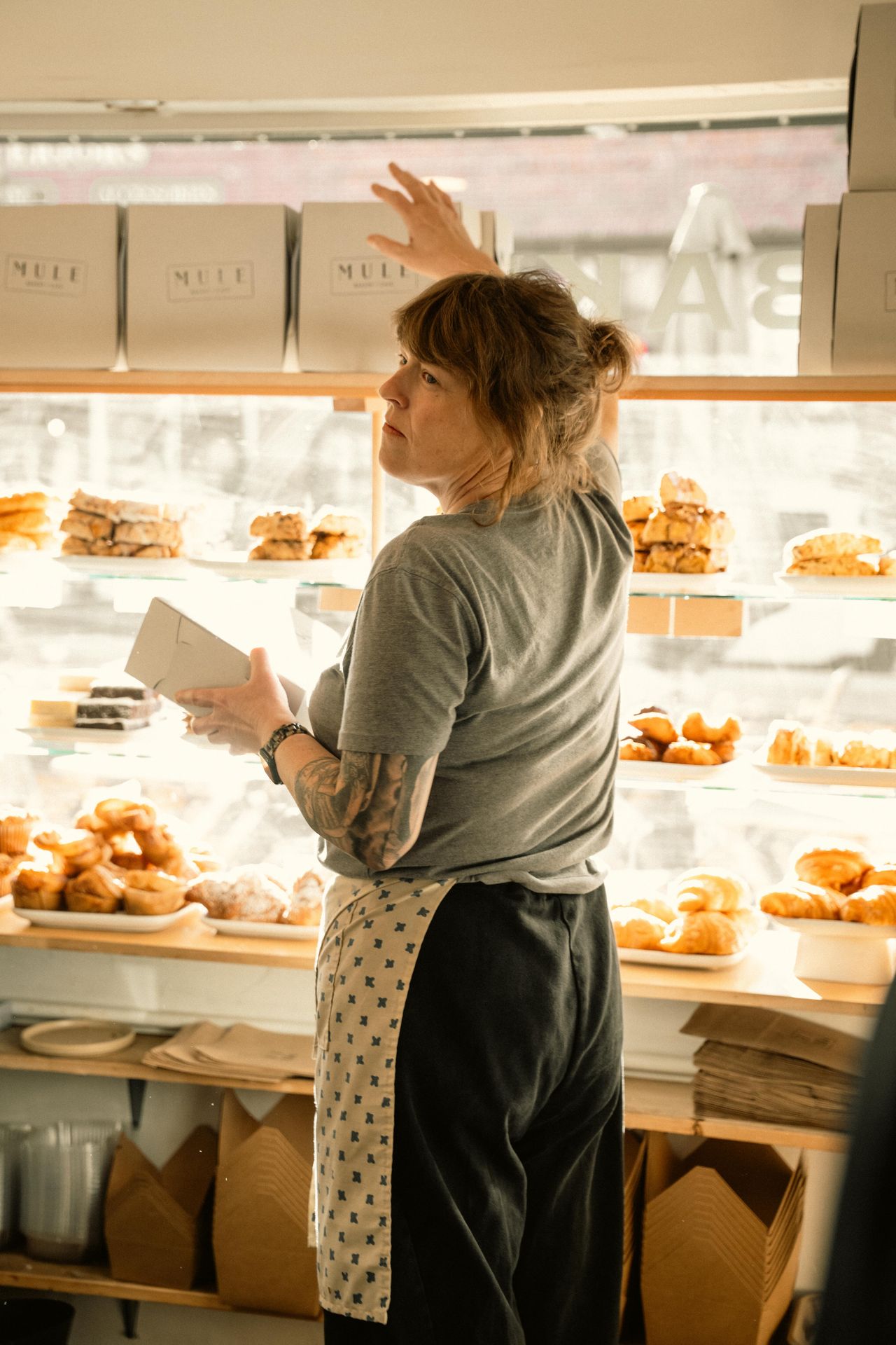 Boulangère rangeant des pâtisseries en vitrine