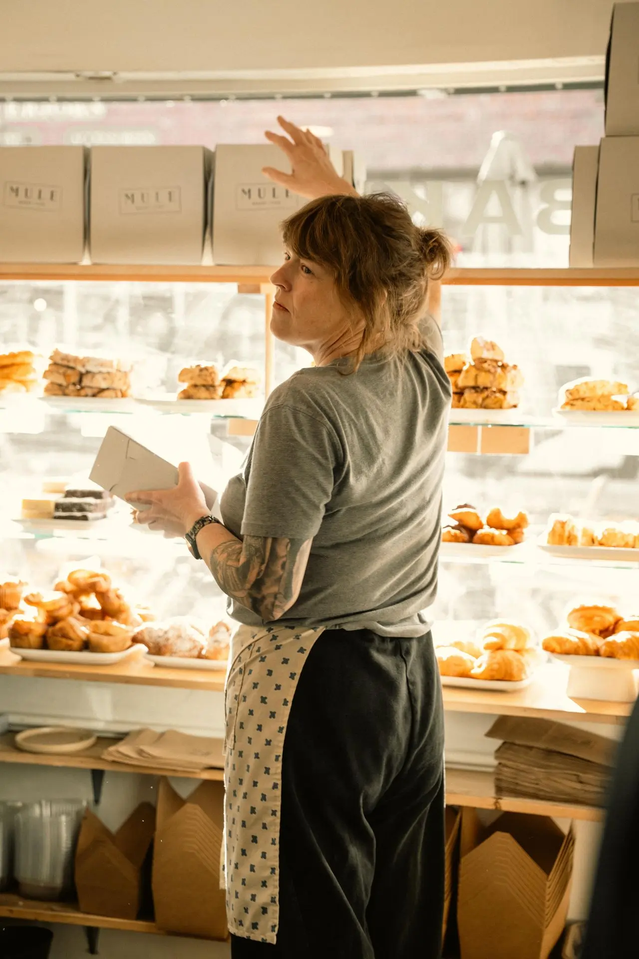 Boulangère rangeant des pâtisseries en vitrine